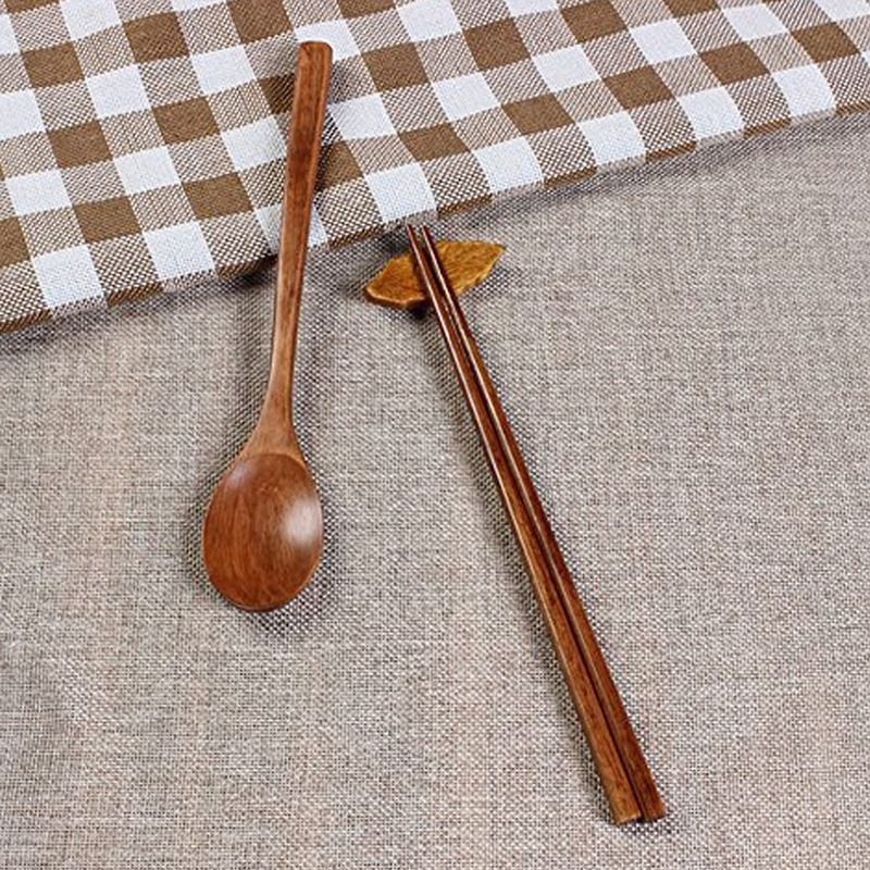Cuillère et paire de baguettes en bois de jujubier sur une nappe beige, avec un repose-baguettes en forme de feuille.